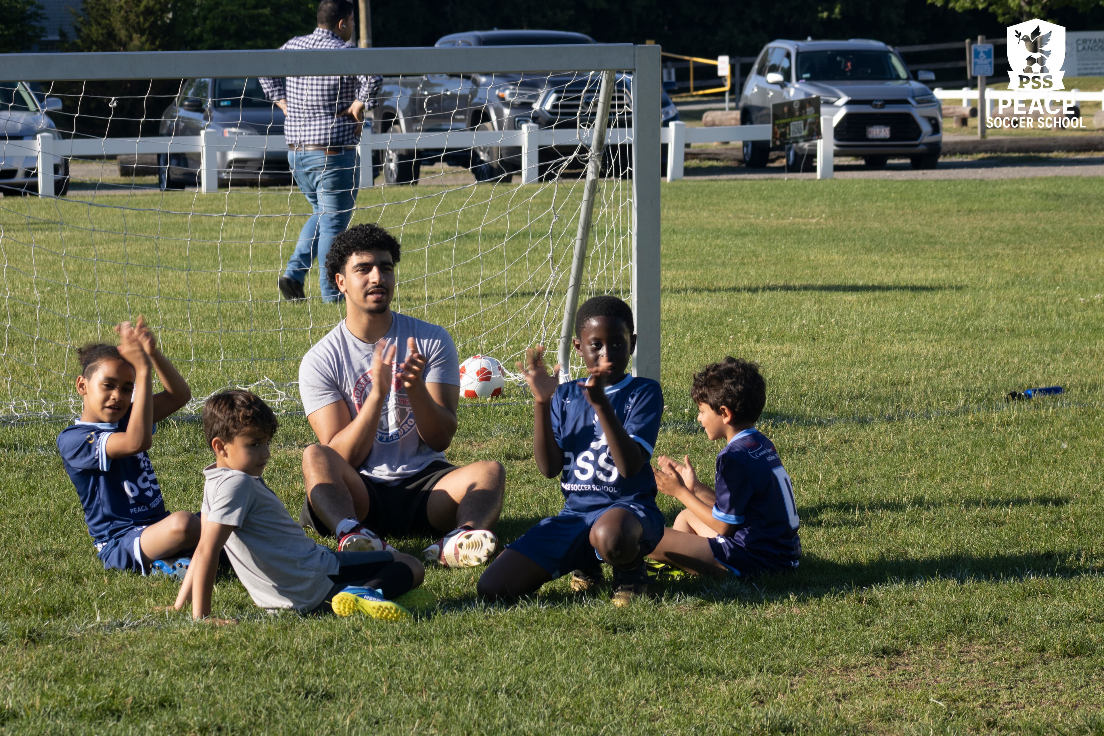 Coach leading faith-based devotional with youth soccer players at Peace Soccer School