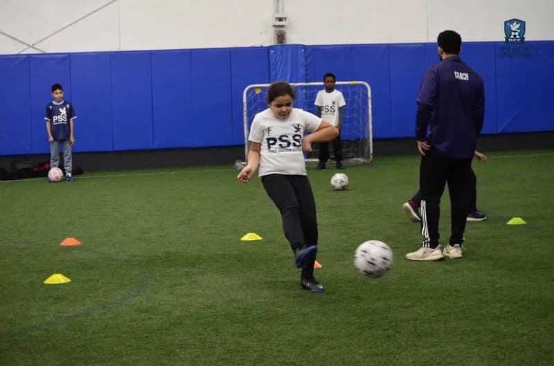 Christian youth soccer coach helping young player with technique